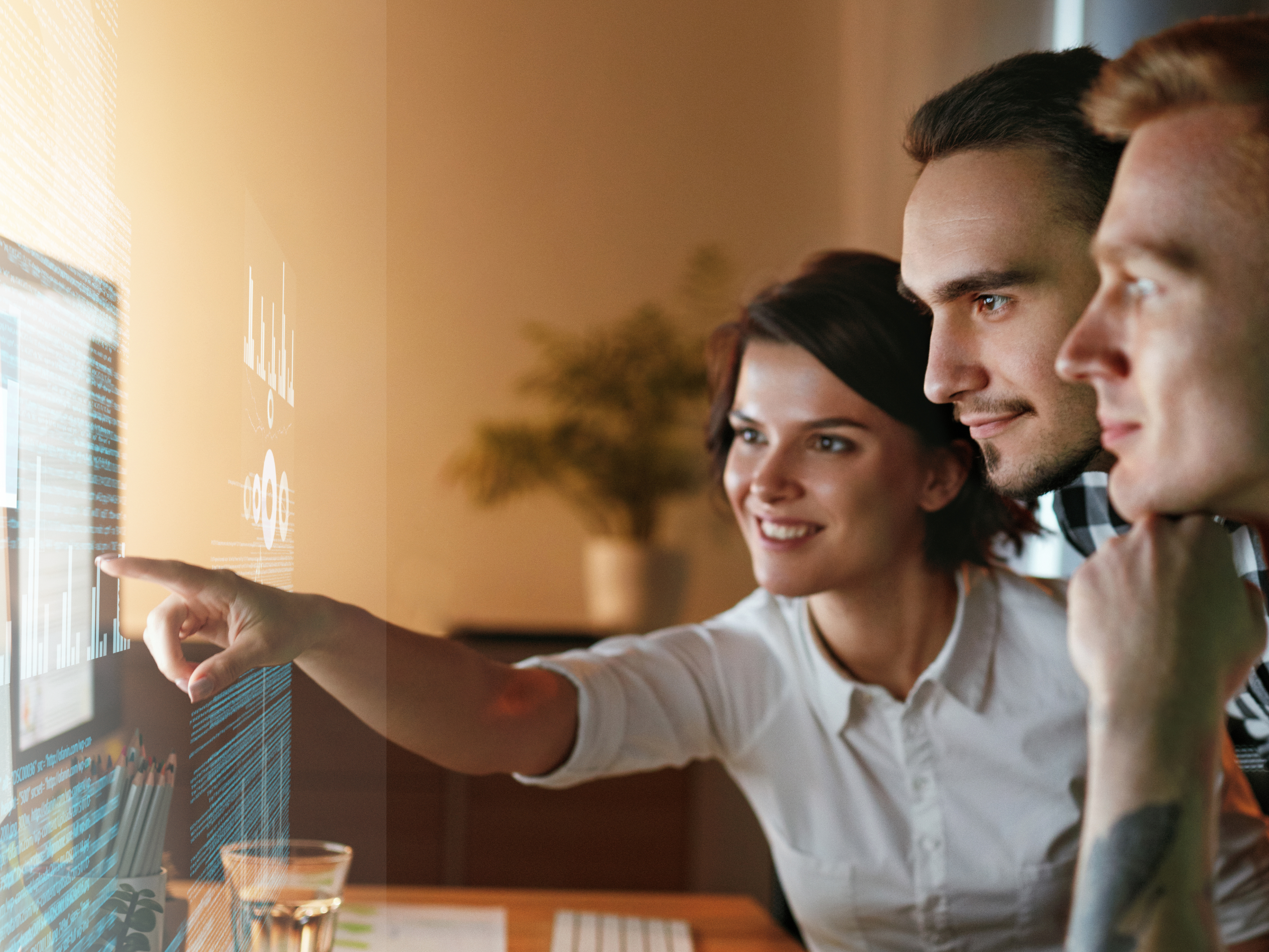 Drei Entwickler konzentriert und diskutieren vor einem Bildschirm mit Code und Datenvisualisierungen